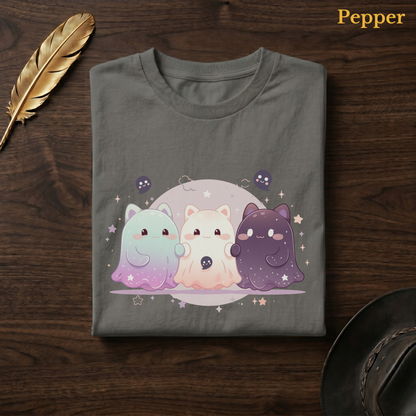 Dreamy ghost shirt in Pepper, a warm grey-charcoal garment-dyed shirt folded flat on dark walnut wood beside a gold feather and a leather hat, the Ghoul Friends galaxy design centred on the chest, labelled Pepper.
