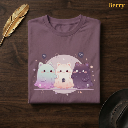 Ghoul Friends tee in Berry, a muted mauve-plum garment-dyed shirt folded flat on dark walnut wood beside a gold feather and a leather hat, the starry cat-ghost design on the chest, labelled Berry.
