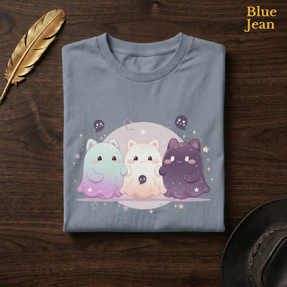 Sparkly ghost shirt in Blue Jean, a faded denim-blue garment-dyed shirt folded flat on dark walnut wood beside a gold feather and a leather hat, the Ghoul Friends moon and stars design on the chest, labelled Blue Jean.
