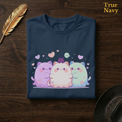 Best friend ghost tee in True Navy, a deep navy garment-dyed shirt folded flat on dark walnut wood beside a gold feather and a leather hat, the pastel cat-ghost trio design on the chest, labelled True Navy.
