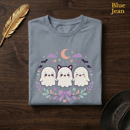 Ghost friends shirt in Blue Jean, a faded denim-blue garment-dyed shirt folded flat on dark walnut wood beside a gold feather and a leather hat, the Ghoul Friends trio design on the chest, labelled Blue Jean.