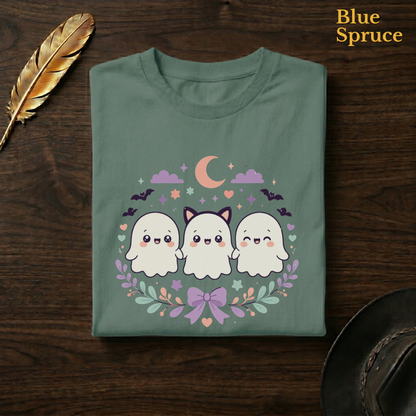Pastel ghost shirt in Blue Spruce, a deep teal-green garment-dyed shirt folded flat on dark walnut wood beside a gold feather and a leather hat, the kawaii ghost squad design on the chest, labelled Blue Spruce.