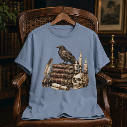 Bookish halloween shirt in Blue Jean on a wooden hanger draped over an antique cane-back chair, set in a richly furnished study with bookshelves, a framed painting, and a brass candlestick, the Poe's Study raven design on the chest.
