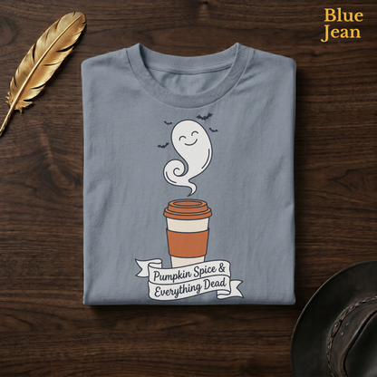 Funny fall tee in Blue Jean, a faded denim-blue garment-dyed shirt folded flat on dark walnut wood beside a gold feather and a leather hat, the Pumpkin Spice & Everything Dead ghost latte design on the chest, labelled Blue Jean.