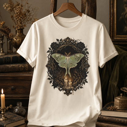 Black rose victorian tee in Ivory on a wooden hanger against an antique interior with a gilded portrait, dried flowers in a brass vase, and stacked books, the painterly skull-moth and candelabra design centred on the chest.
