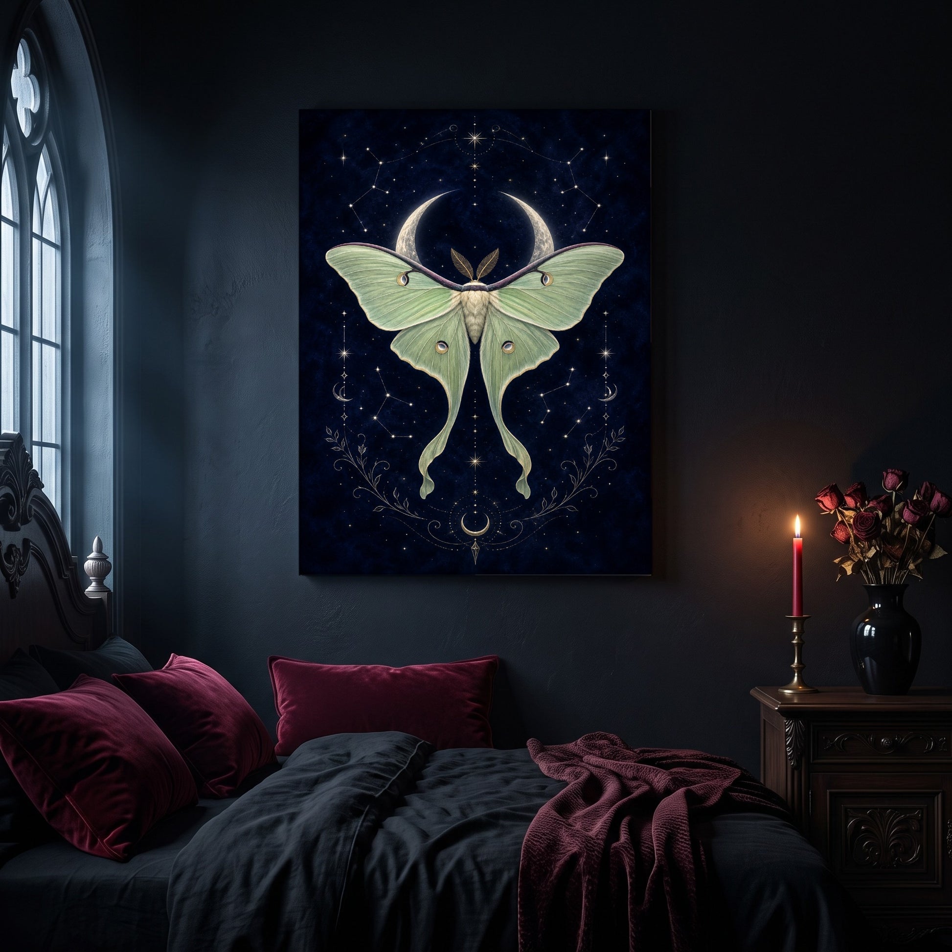 Verdigris luna moth canvas hanging on a dark navy wall in a gothic bedroom, above a bed with burgundy velvet pillows and charcoal bedding, beside an arched leaded window and a wooden nightstand holding a lit red taper candle in a brass holder and a black vase of dried roses.