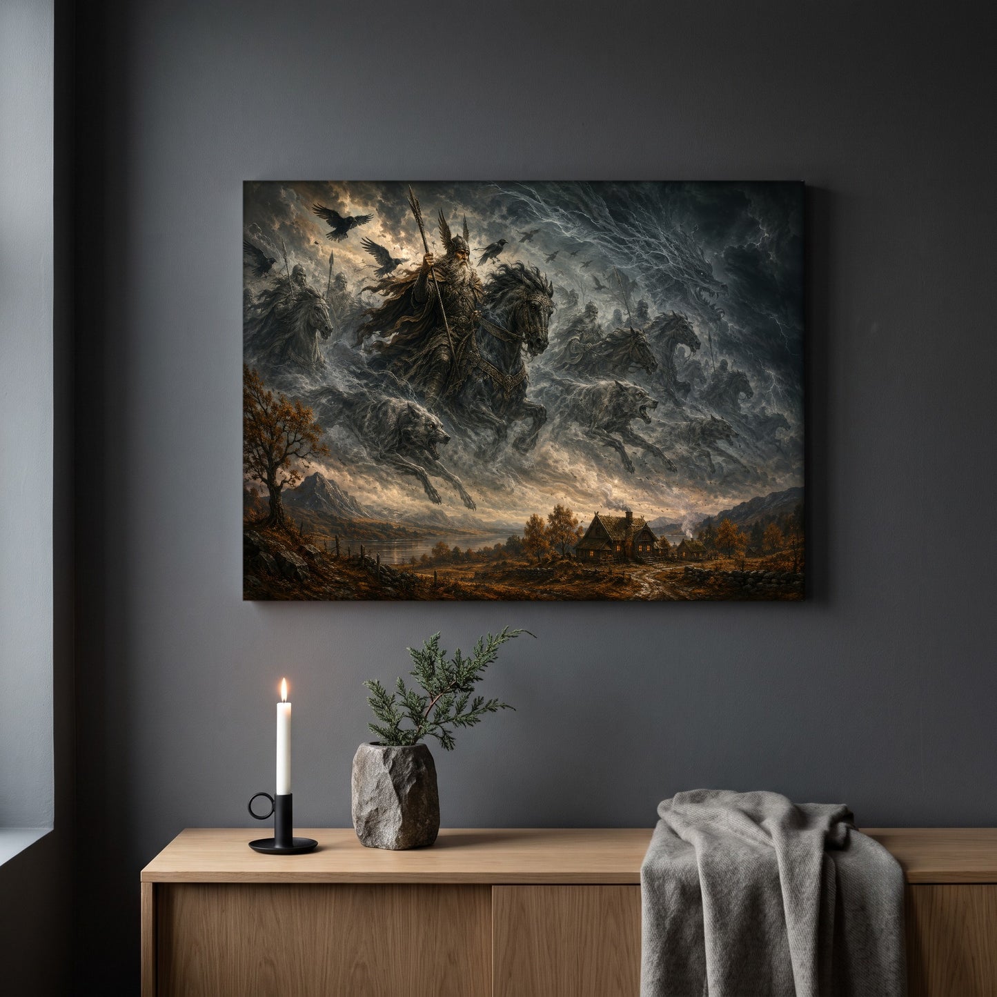 Oskoreia storm riders print hanging on a plain dark grey wall above a light oak sideboard, styled with a lit white taper candle in a black holder, a stone vase of juniper, and a soft grey throw draped over the end.
