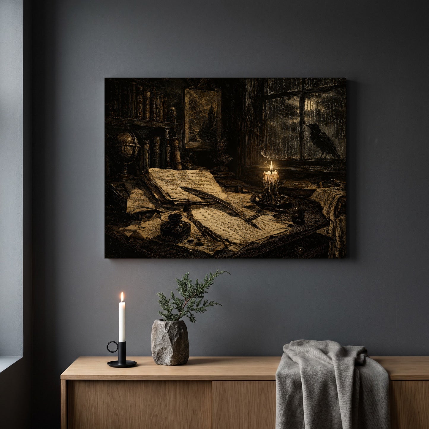 The Unfinished Letter canvas hanging on a plain grey wall above a light oak sideboard, styled with a lit white taper candle in a black holder, a stone vase holding a juniper sprig and a folded grey throw.