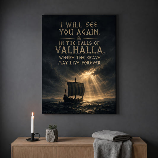 Valhalla Awaits quote print hanging on a plain grey wall above a light oak sideboard, styled with a lit white taper candle in a black holder, a small stone pot of greenery and a folded grey throw.
