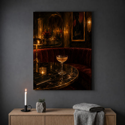Nuit cocktail lounge print hanging on a plain grey wall above a light oak sideboard, styled with a lit white taper candle in a black holder, a small stone pot of greenery and a folded grey throw.