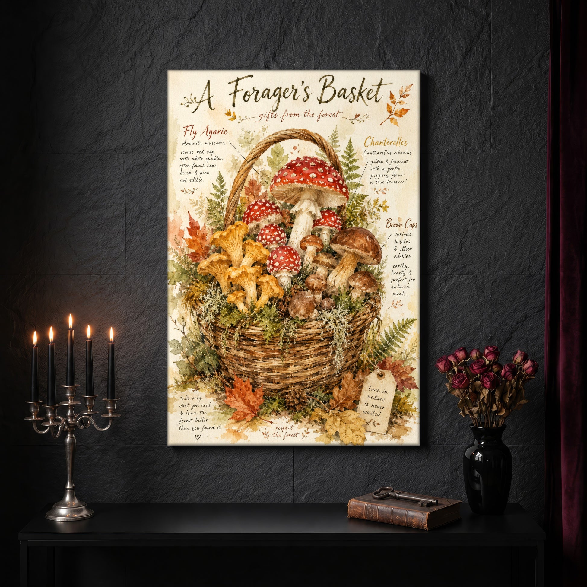 A Forager's Basket canvas on a dark slate stone wall above a black console table, with a five-arm silver candelabra of lit black tapers, an antique iron key resting on a worn leather book, and a black vase of dried roses beside a burgundy velvet curtain.