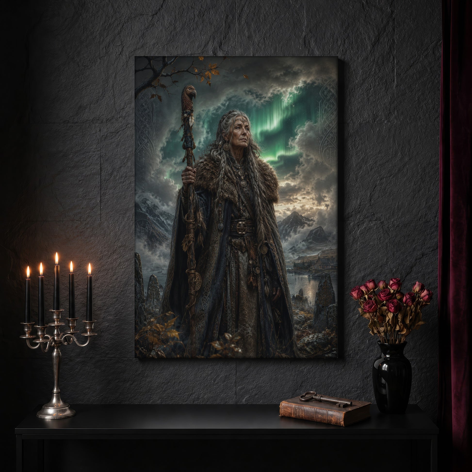 Spákona canvas on a dark slate stone wall above a black console table, with a five-arm silver candelabra of lit black tapers, an antique iron key resting on a worn leather book, and a black vase of dried roses beside a burgundy velvet curtain.