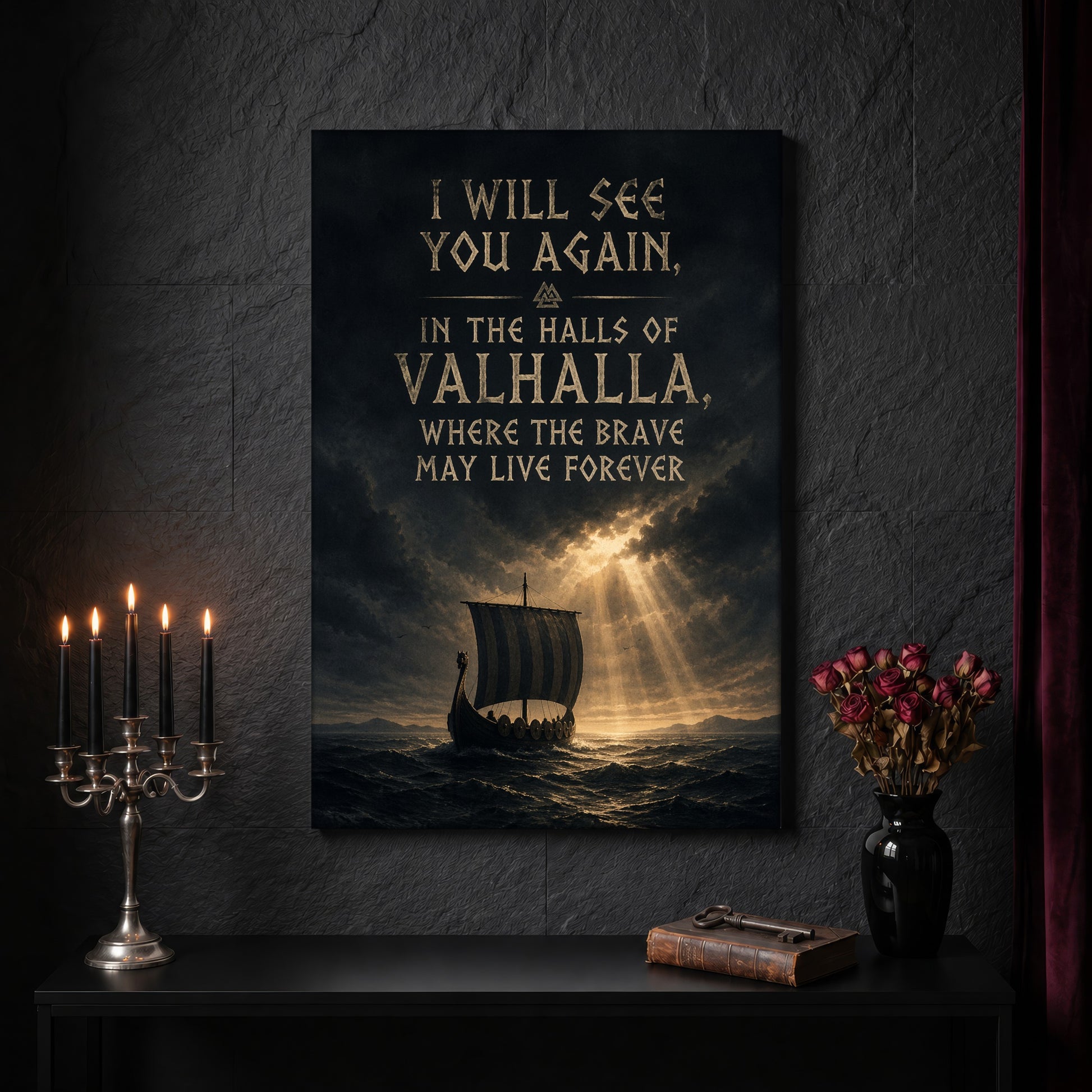 Valhalla Awaits canvas on a dark slate stone wall above a black console table, with a five-arm silver candelabra of lit black tapers, an antique iron key resting on a worn leather book, and a black vase of dried roses beside a burgundy velvet curtain.