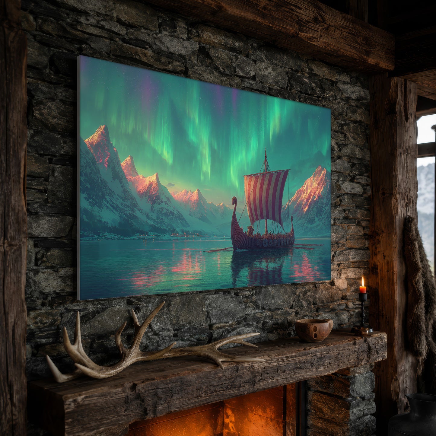 Vinland wide aurora canvas hanging on a rough stone chimney breast above a rustic timber mantel, with large shed antlers, a carved wooden bowl and a lit red candle along the beam, firelight glowing from the hearth below and a mountain window to the right.