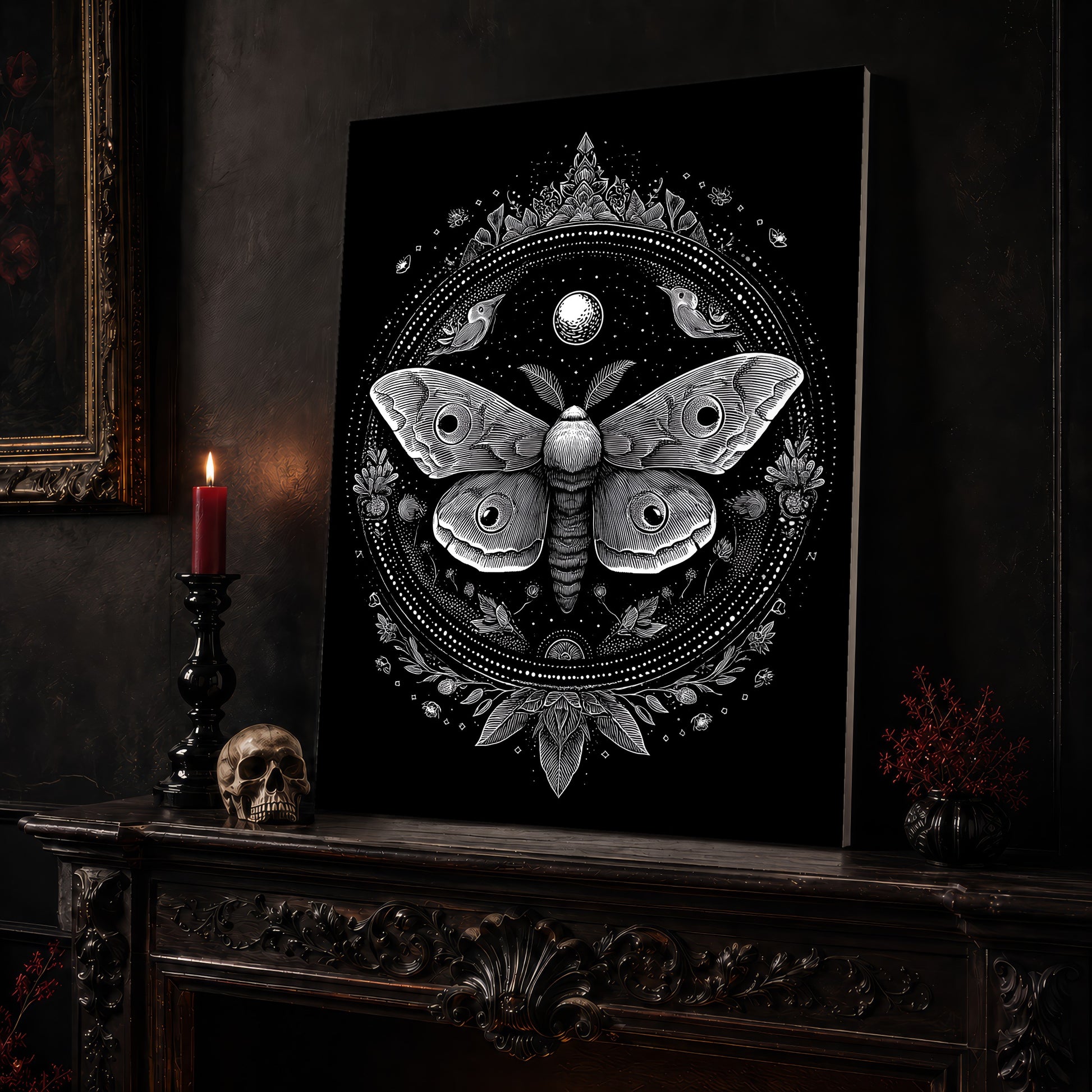 Vespers moth mandala canvas leaning on a dark carved mantel beside a lit dark red taper in a black candlestick, a bone-coloured skull, and a small black vase of red berry sprigs, with a gilt-framed painting on the wall alongside.