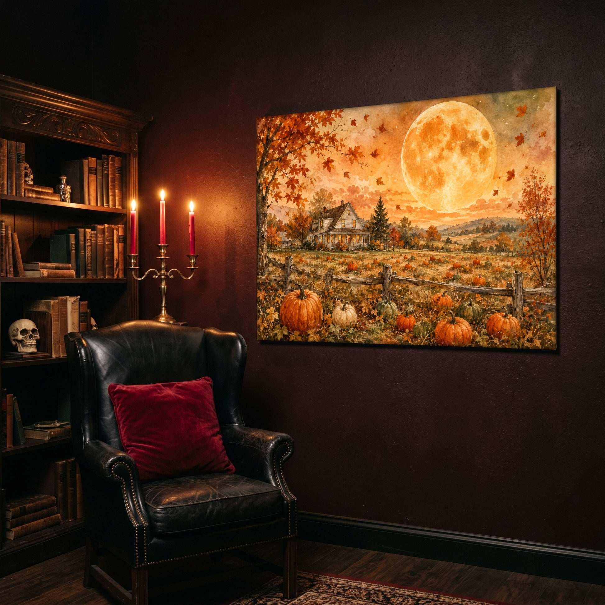 Homestead Moonrise canvas hanging on a deep oxblood wall above a black leather wingback chair with a red velvet cushion, beside a bookcase of antique books, three lit pink taper candles and a skull resting on the shelf.