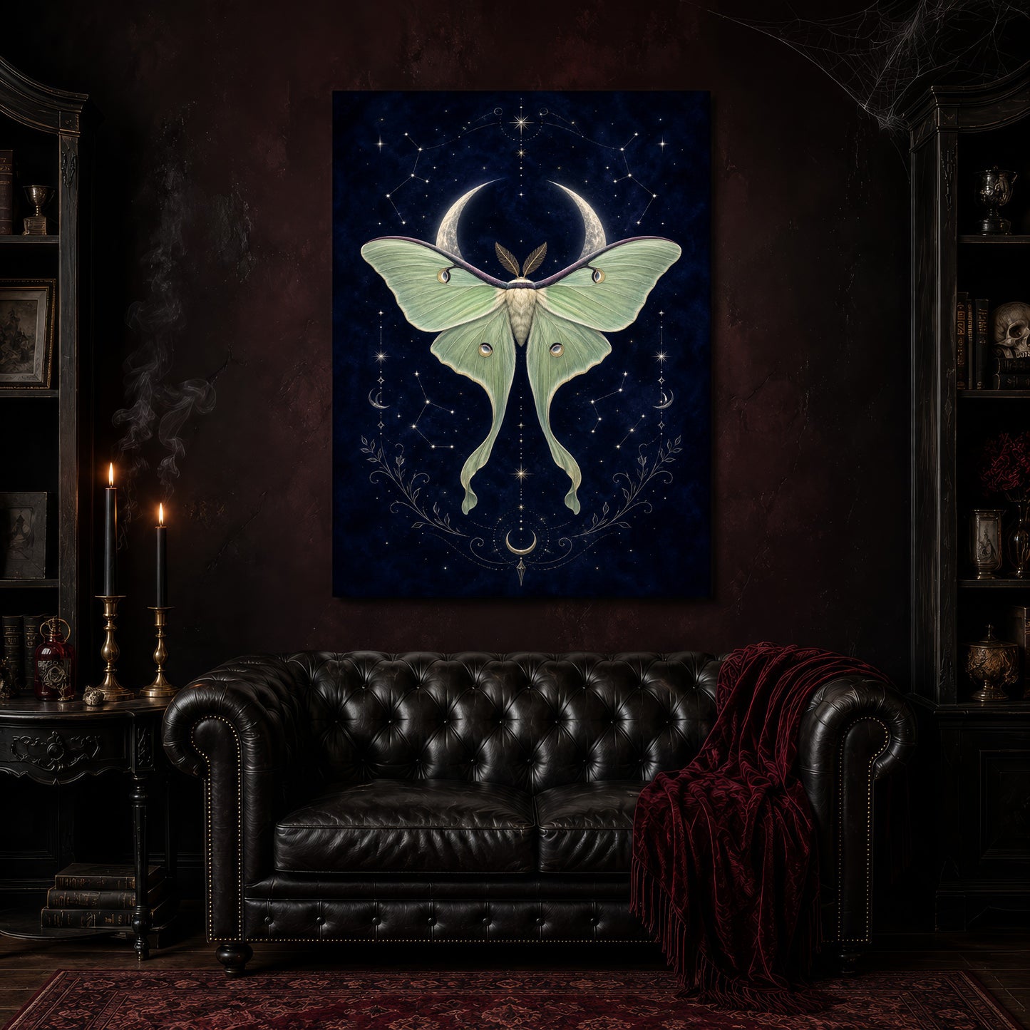 Verdigris moth and moon canvas hanging above a black tufted Chesterfield sofa draped with a red fringed velvet throw, in a cobwebbed oxblood parlour with brass candlesticks, dark cabinets of books and goblets, and a patterned red rug.