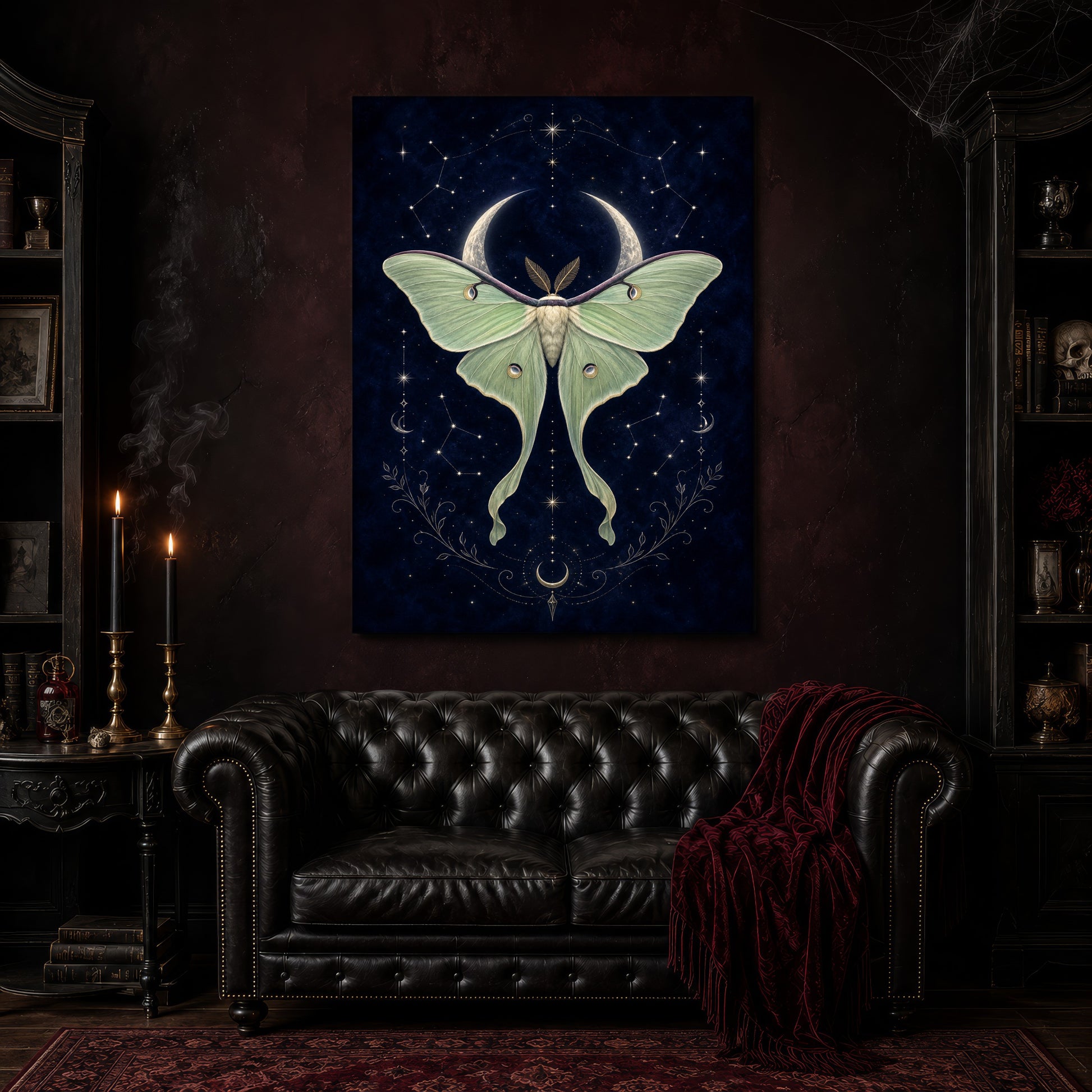 Verdigris moth and moon canvas hanging above a black tufted Chesterfield sofa draped with a red fringed velvet throw, in a cobwebbed oxblood parlour with brass candlesticks, dark cabinets of books and goblets, and a patterned red rug.