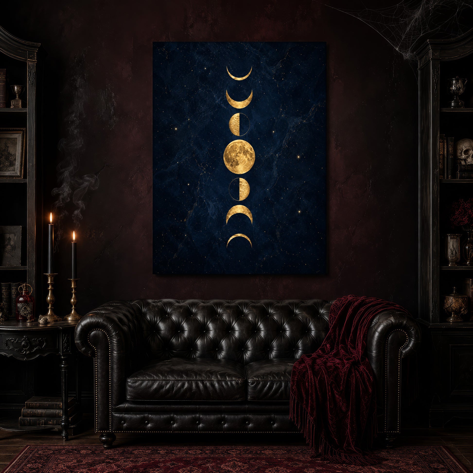 Lunarium gold moon canvas hanging above a black tufted Chesterfield sofa draped with a red fringed velvet throw, in a cobwebbed oxblood parlour with brass candlesticks, dark cabinets of books and goblets, and a patterned red rug.